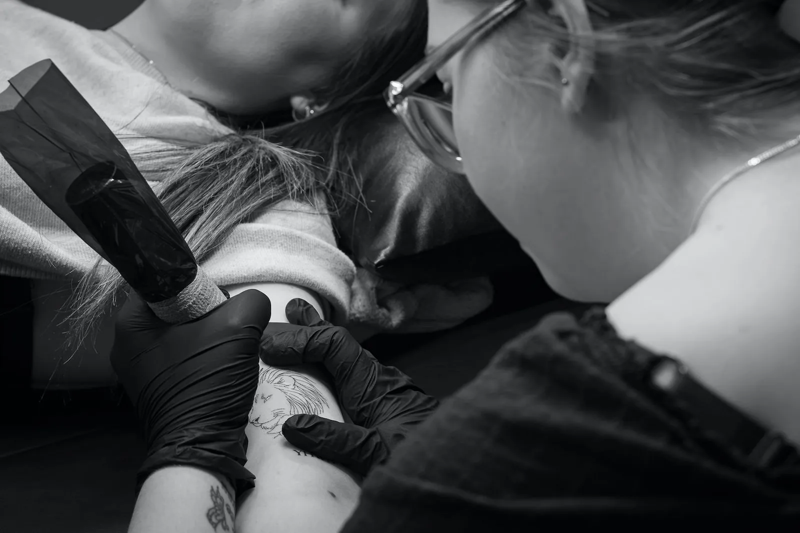 fine line tattoo artist working on a delicate lion tattoo on a bicep